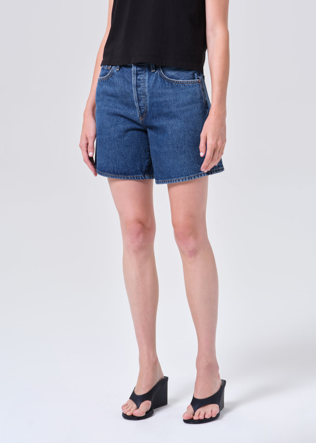 Person wearing blue denim shorts on a white background