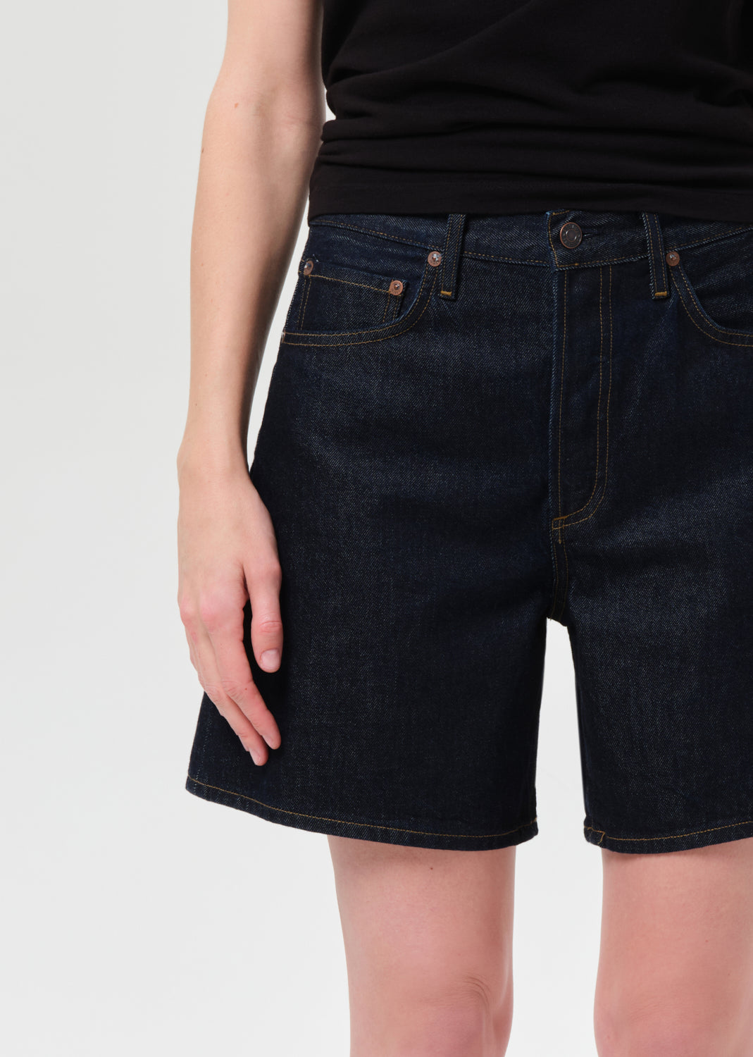 Person wearing dark blue denim shorts on a light gray background