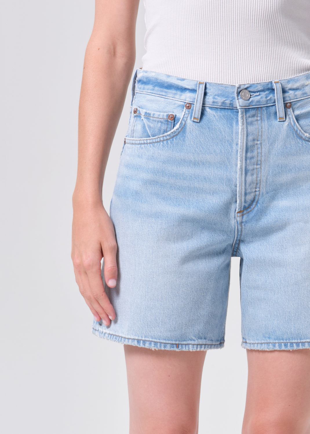 Light blue denim shorts worn by a person on a plain background