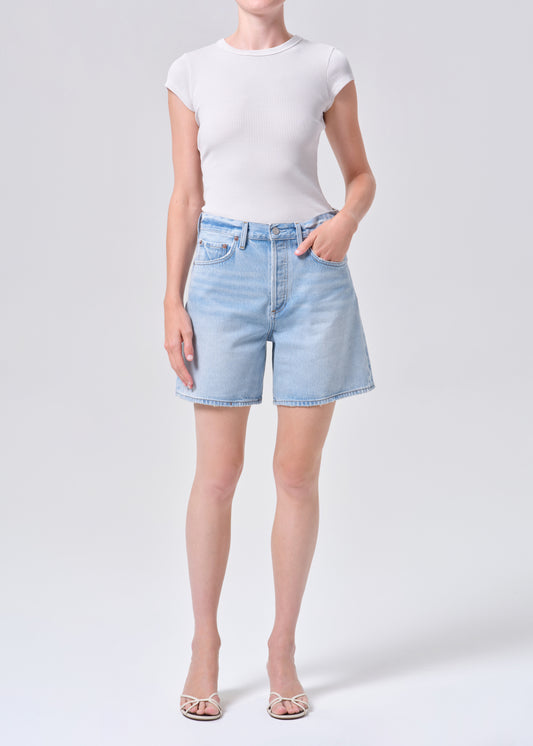 Person wearing light blue denim shorts and a white t-shirt on a white background