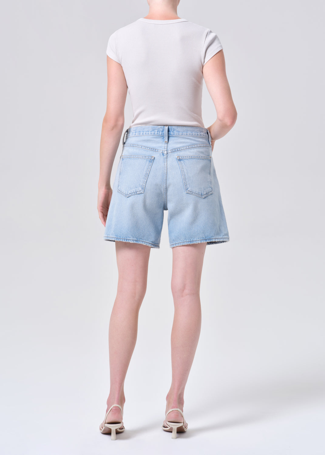 Person wearing light blue denim shorts and a white t-shirt on a plain background