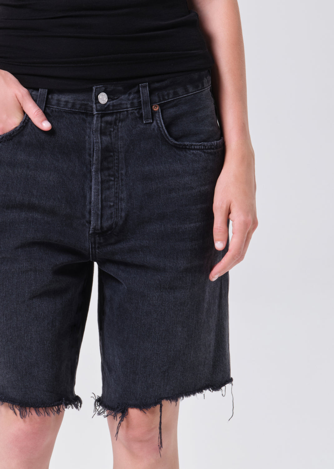 Black denim shorts worn by a person on a white background