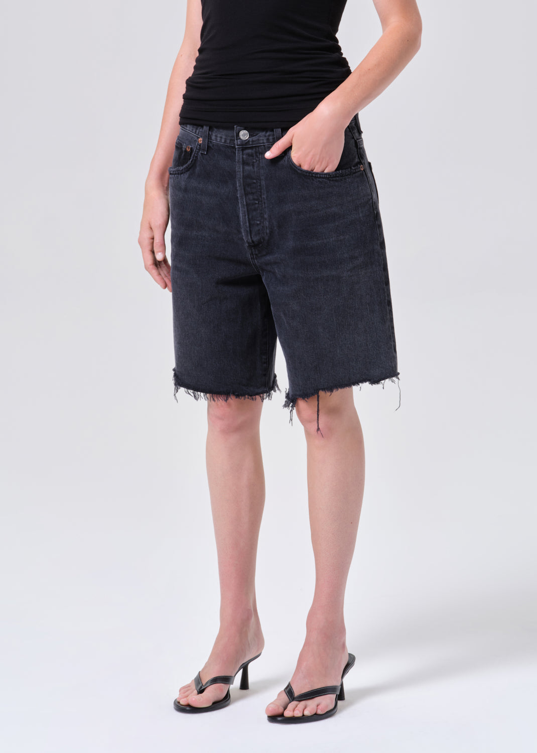 Person wearing black denim shorts on a white background