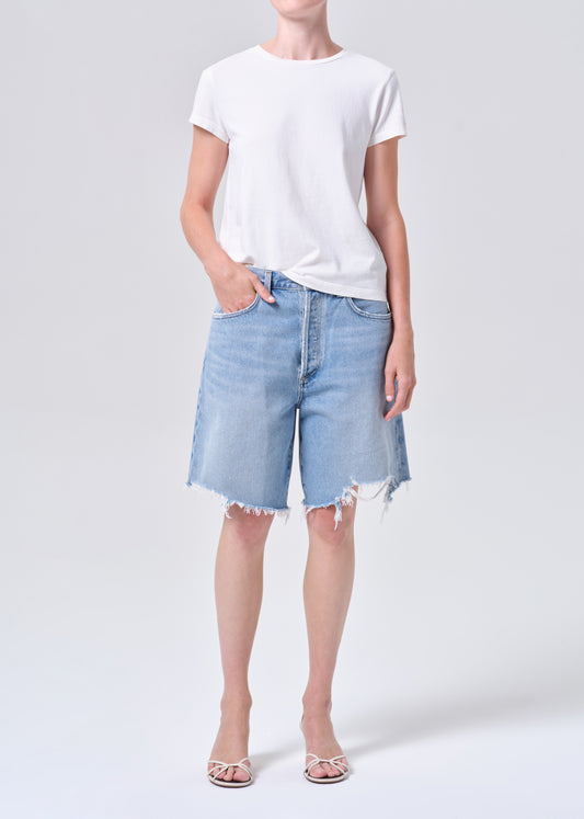 Person wearing a white t-shirt and light blue denim shorts on a white background