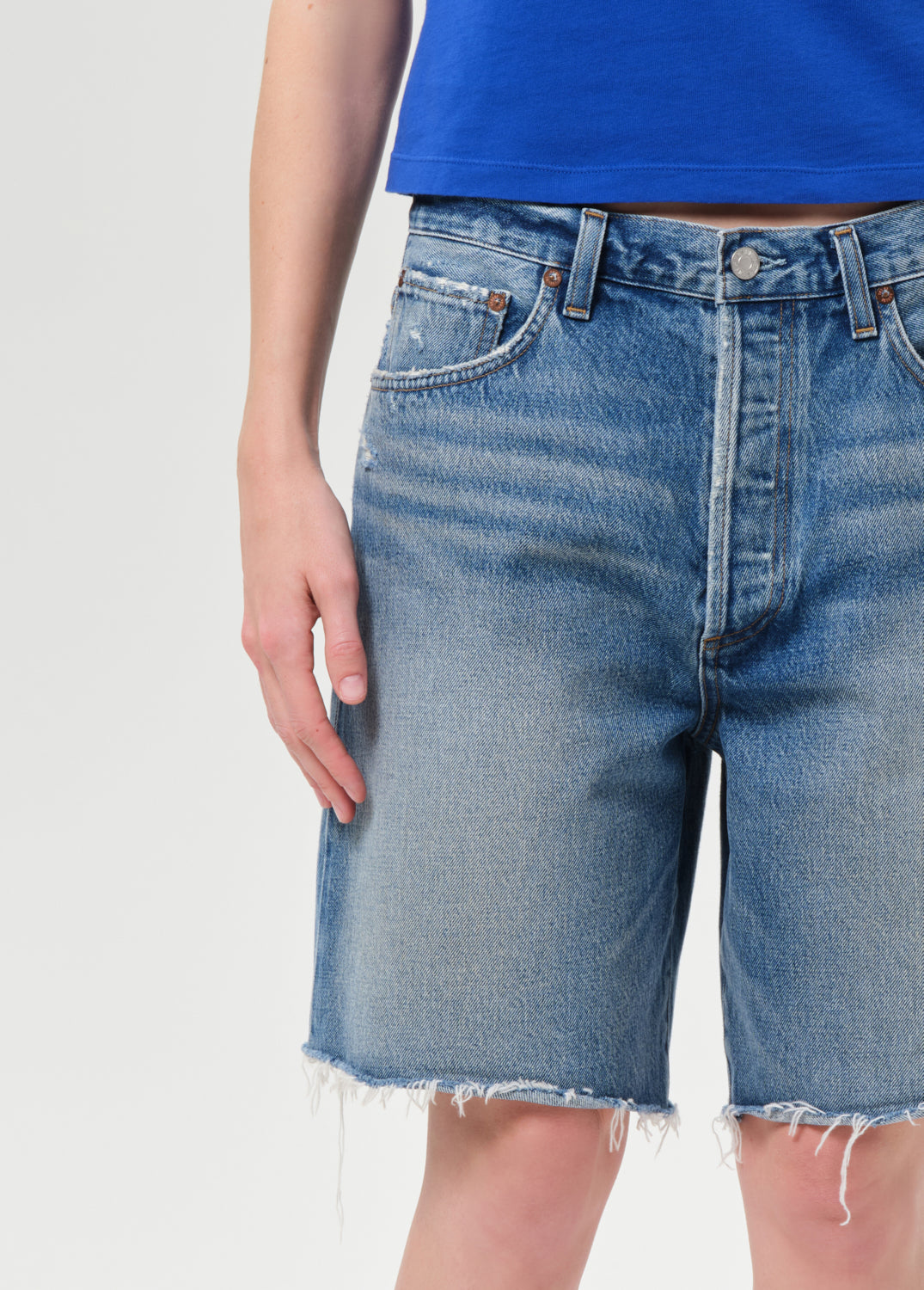 Blue denim shorts worn by a person on a light gray background