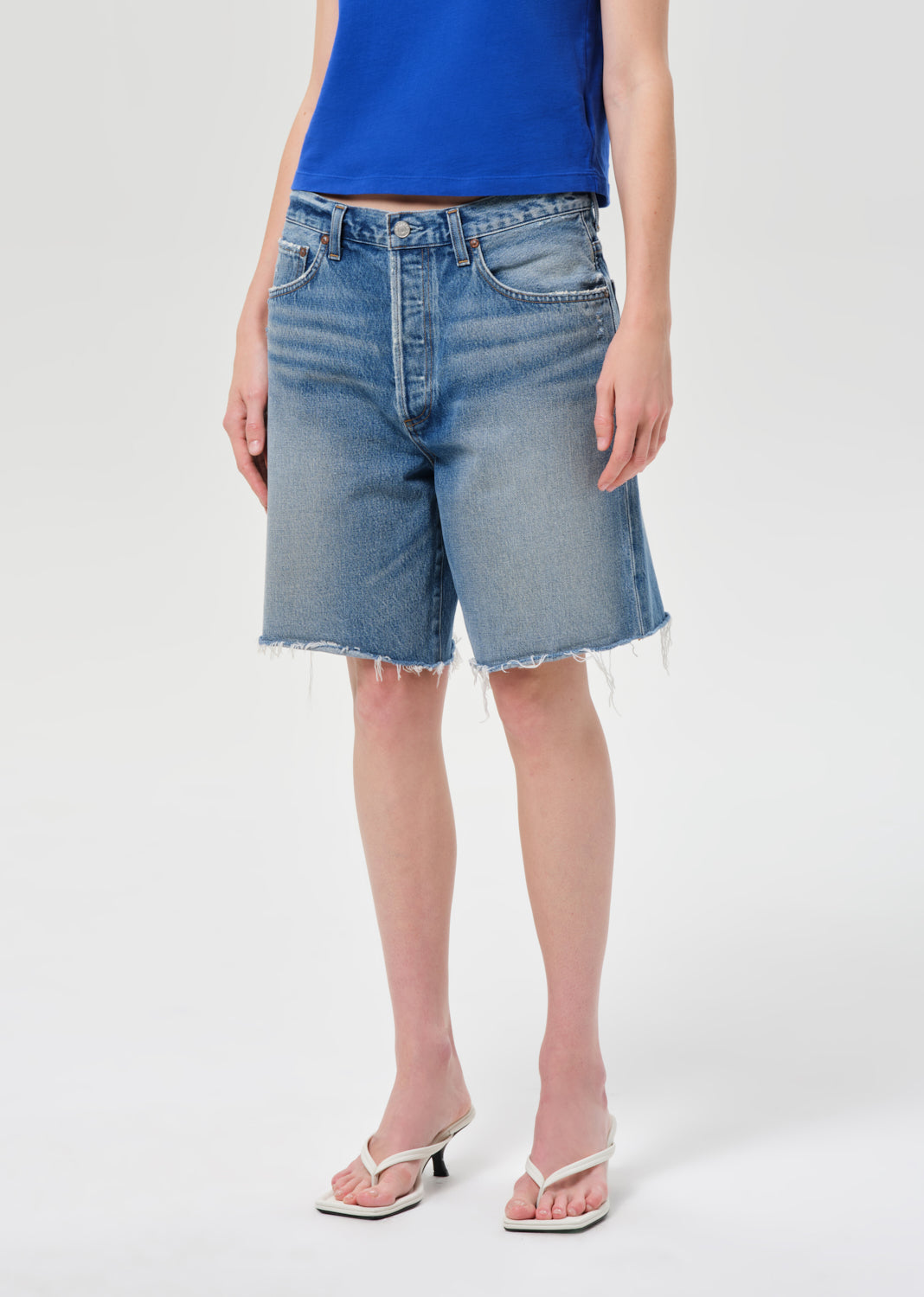 Person wearing blue denim shorts on a white background