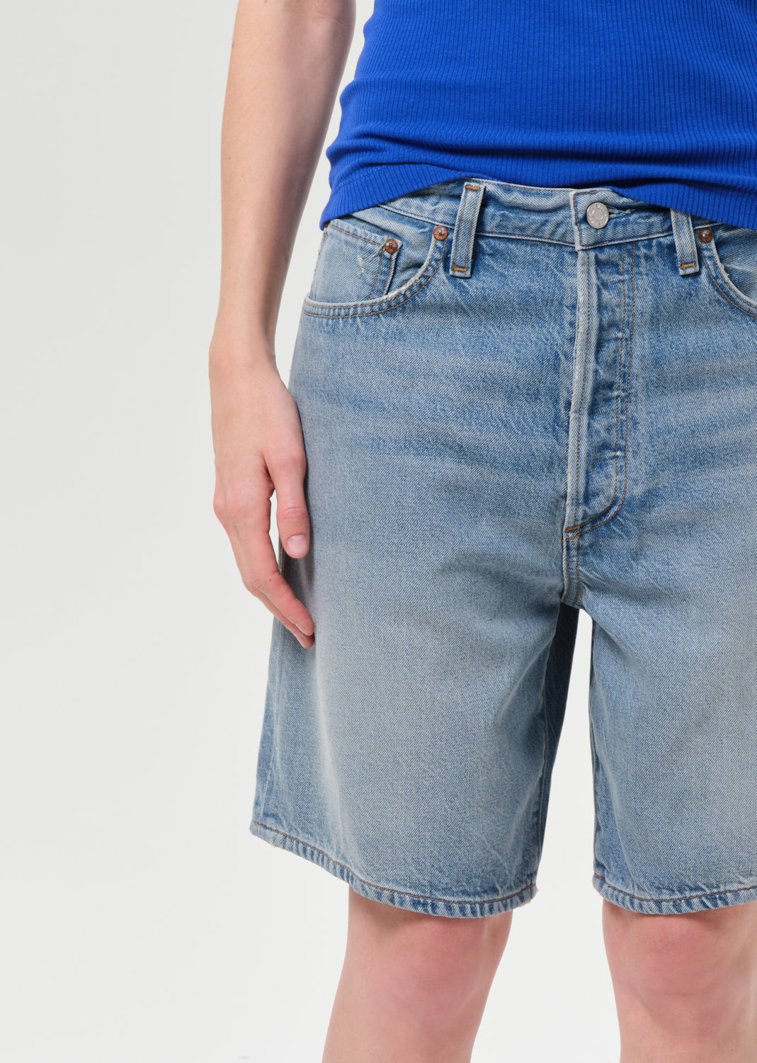 Blue denim shorts worn by a person on a light gray background