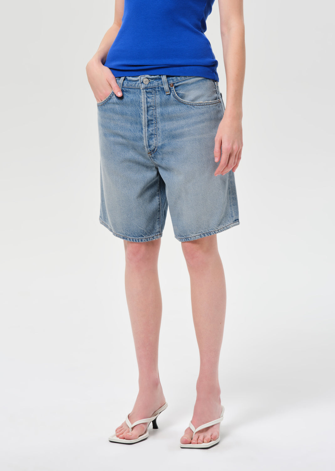 Person wearing light blue denim shorts on a white background