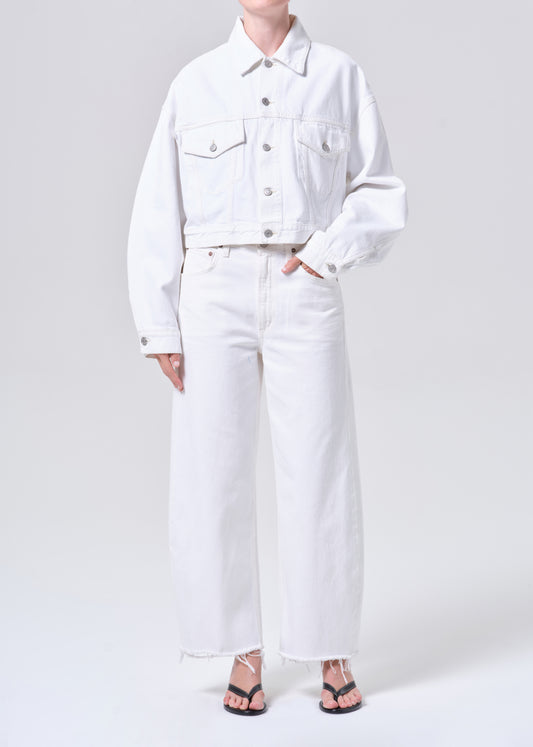 Person wearing a white denim jacket and pants on a plain background