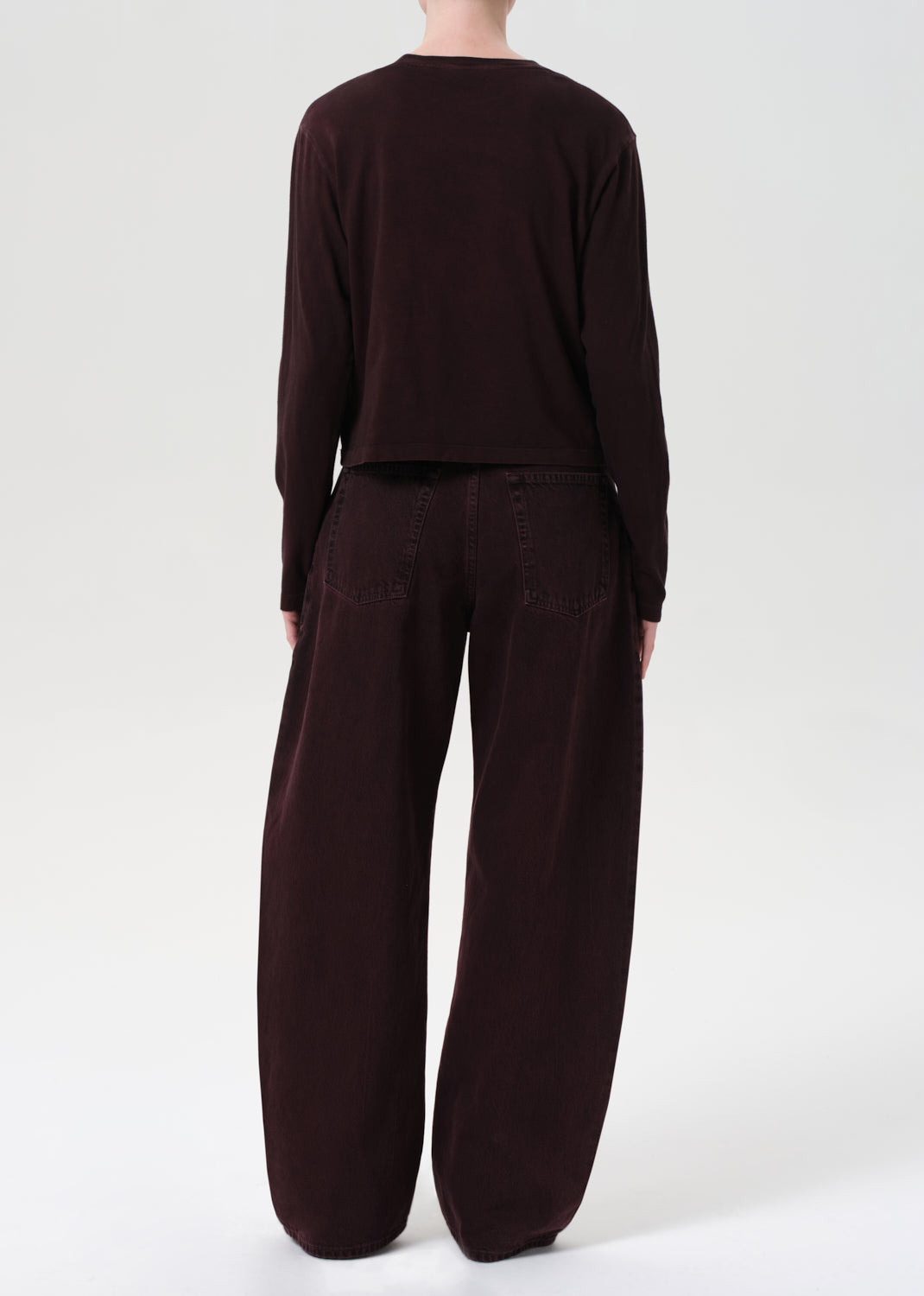 Person wearing a brown outfit with wide-leg pants on a white background