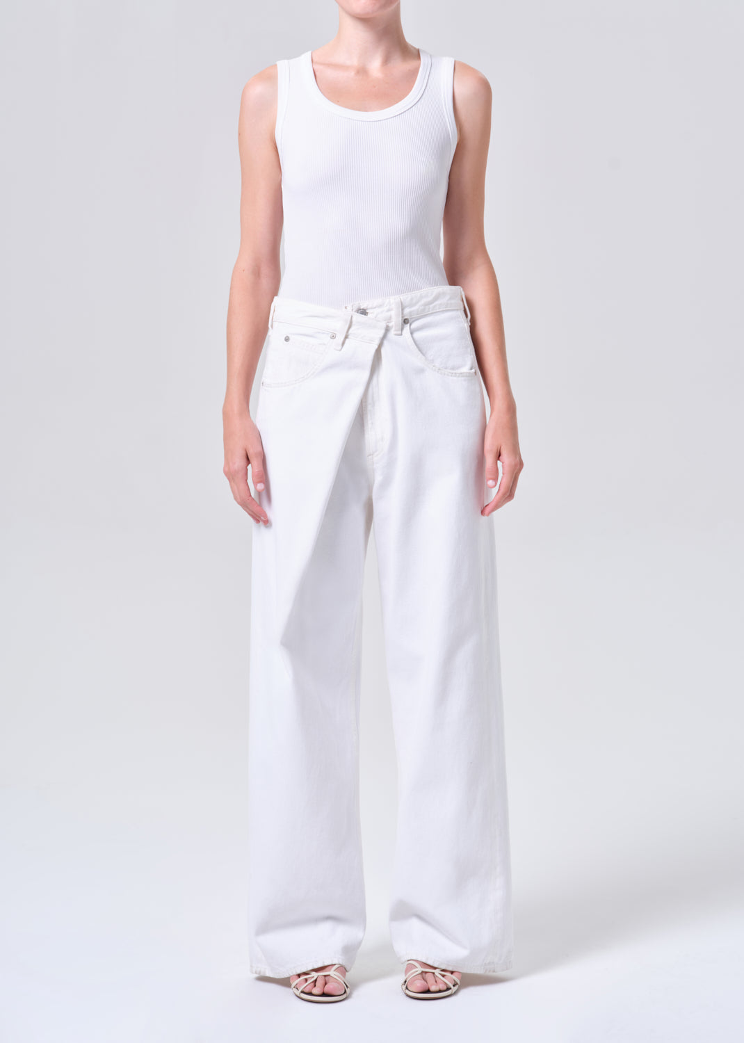 Person wearing a white tank top and wide-leg pants on a white background