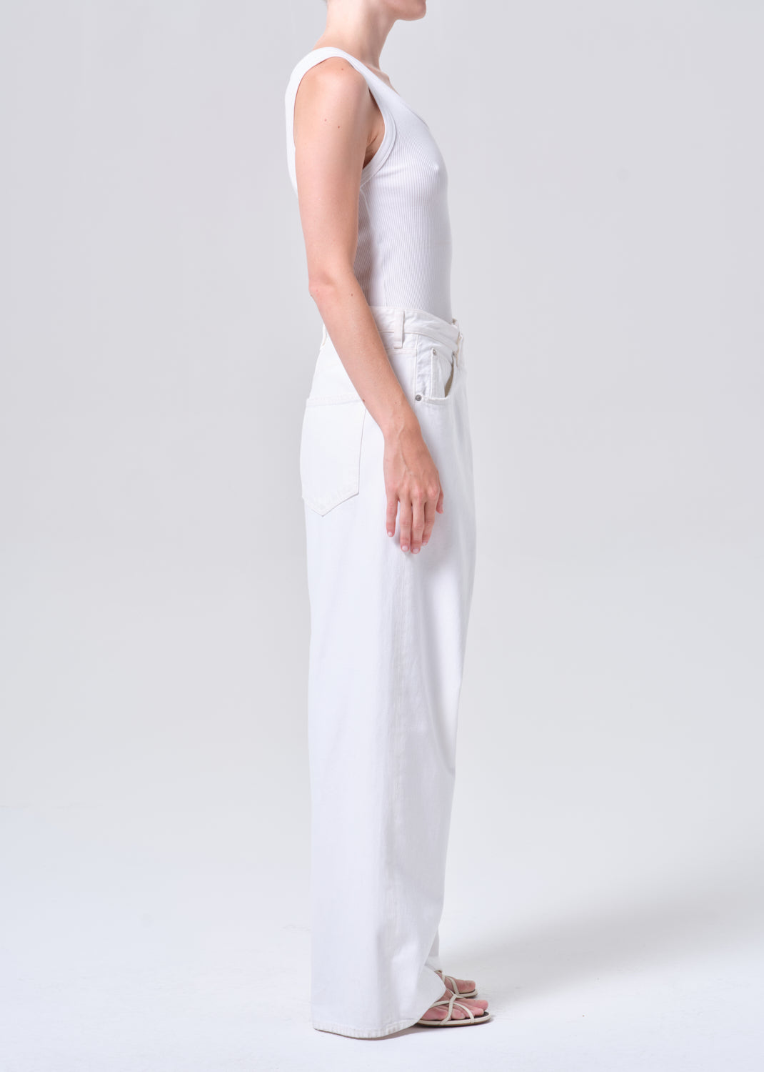 Person wearing a white sleeveless top and wide-leg pants on a plain background
