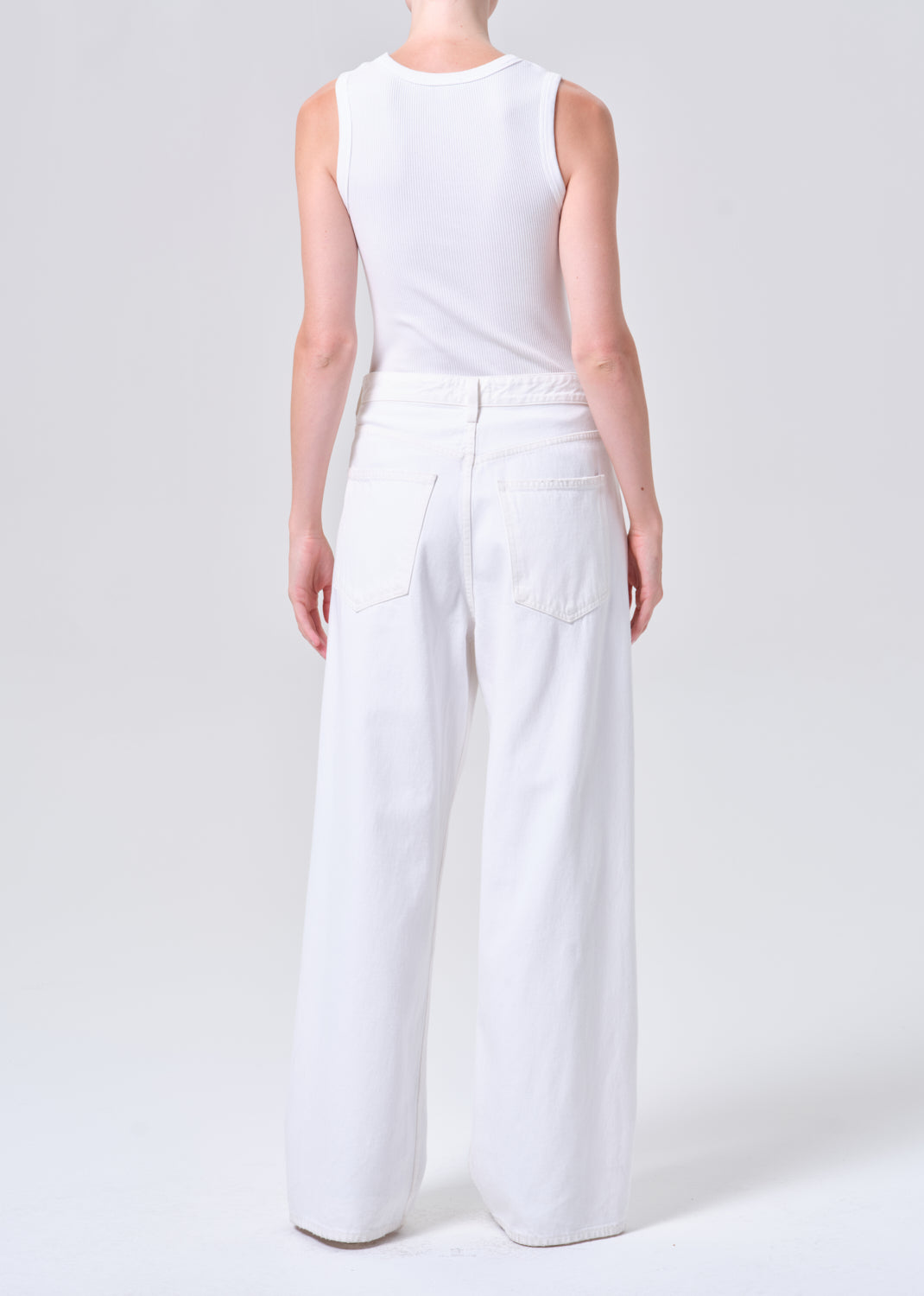 Person wearing a white sleeveless top and wide-leg pants on a light gray background