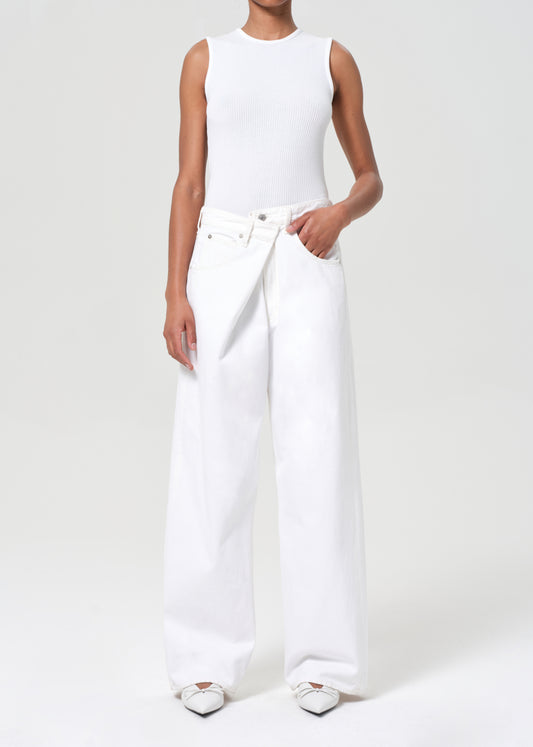 Person wearing a white sleeveless top and wide-leg pants on a plain background