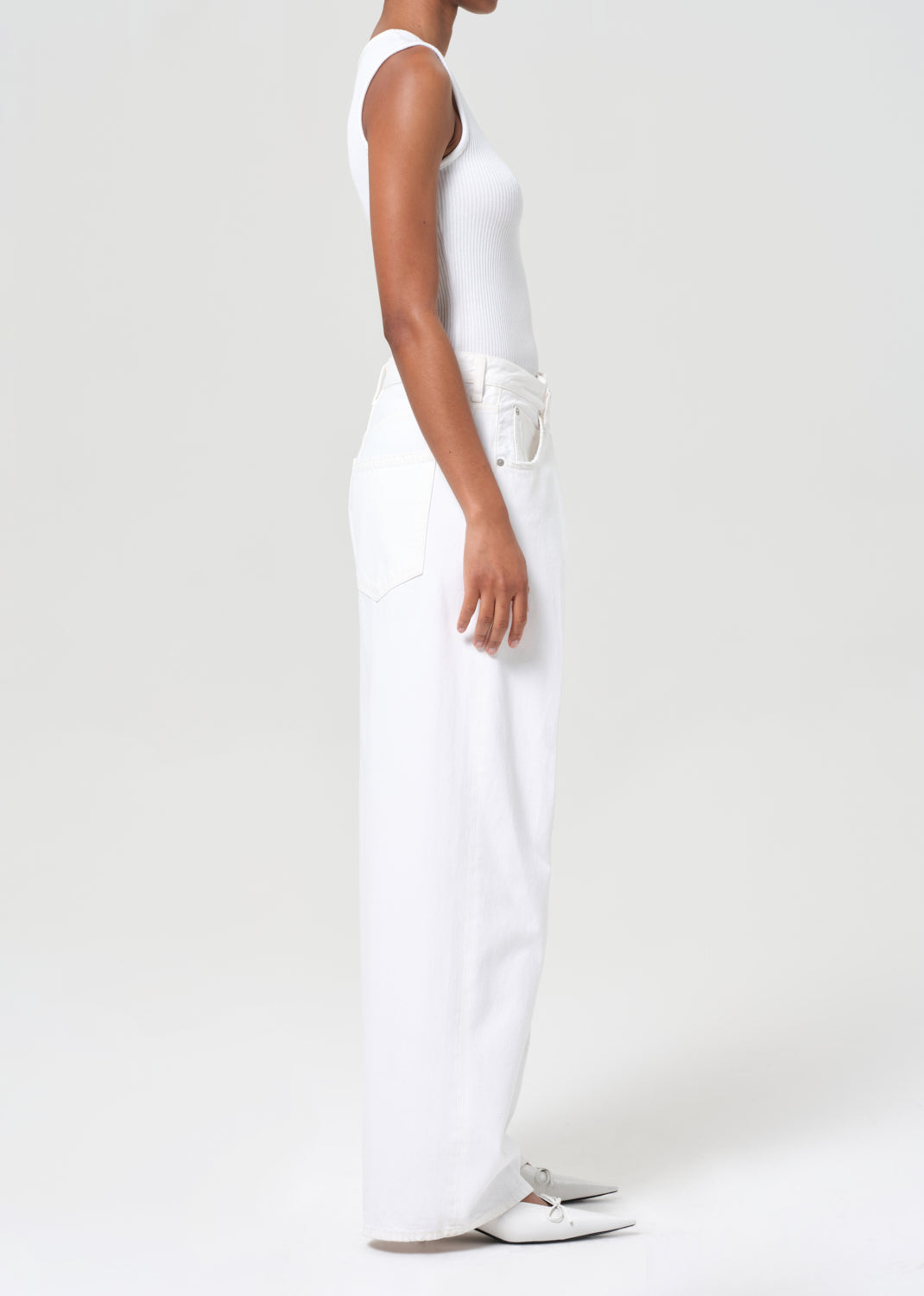 Person wearing a white sleeveless top and pants on a plain background