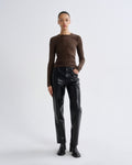 Person wearing a brown long-sleeve top and black leather pants on a white background