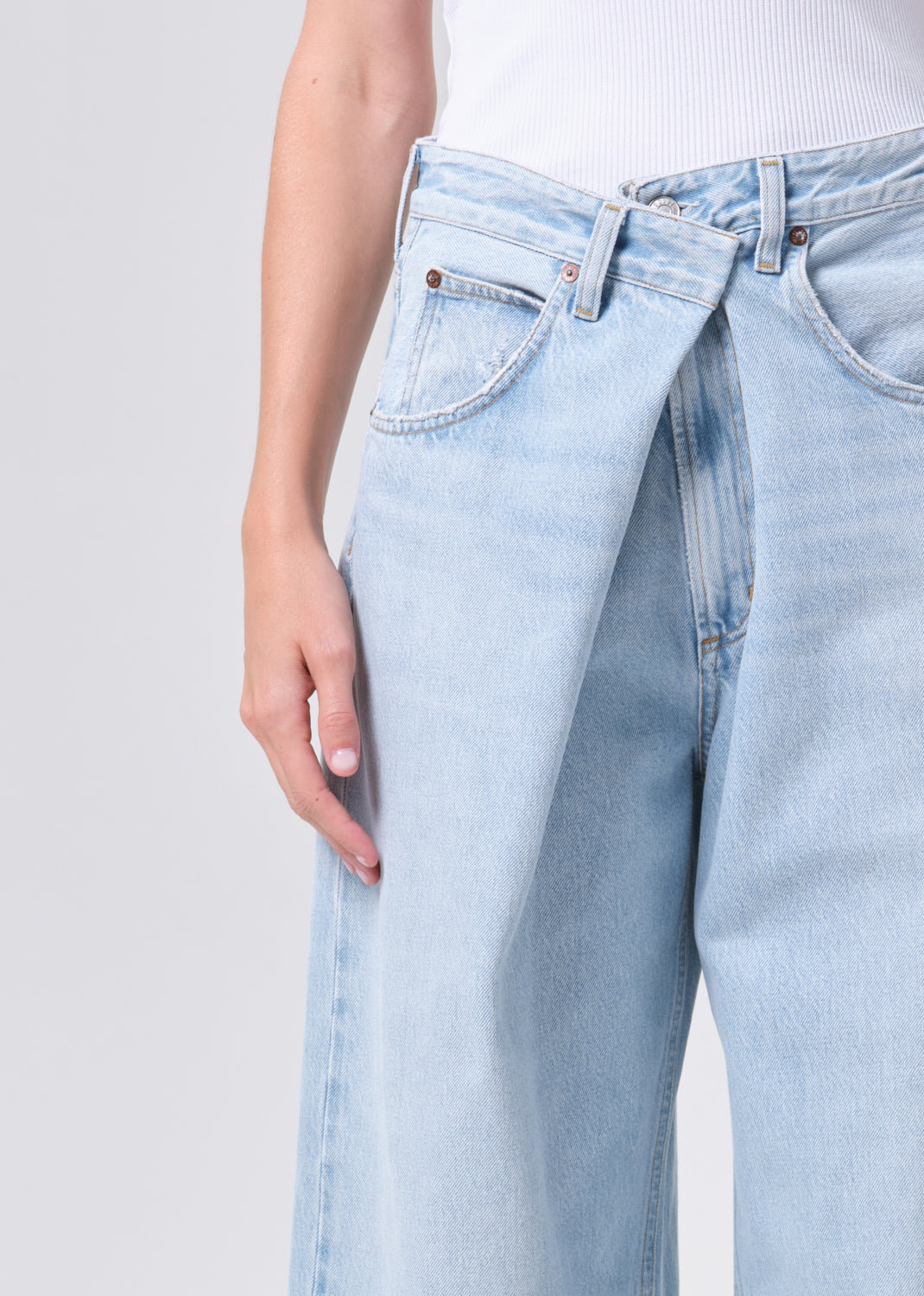 Light blue jeans worn by a person on a plain background