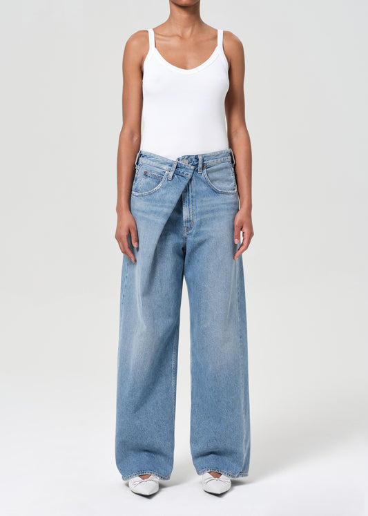 Person wearing a white tank top and blue jeans on a white background