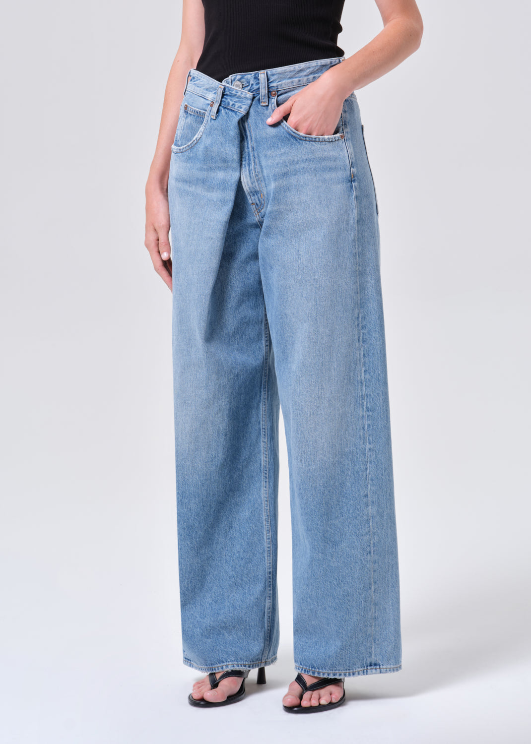 Person wearing light blue jeans on a white background