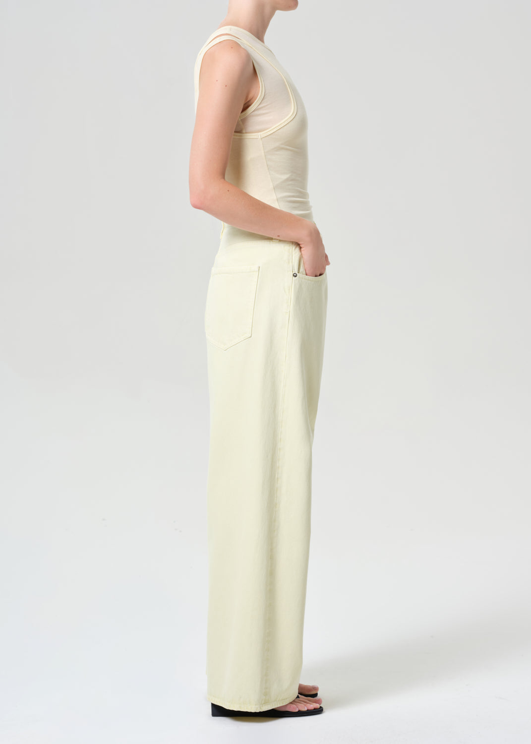 Person wearing a light-colored sleeveless top and wide-leg pants on a white background