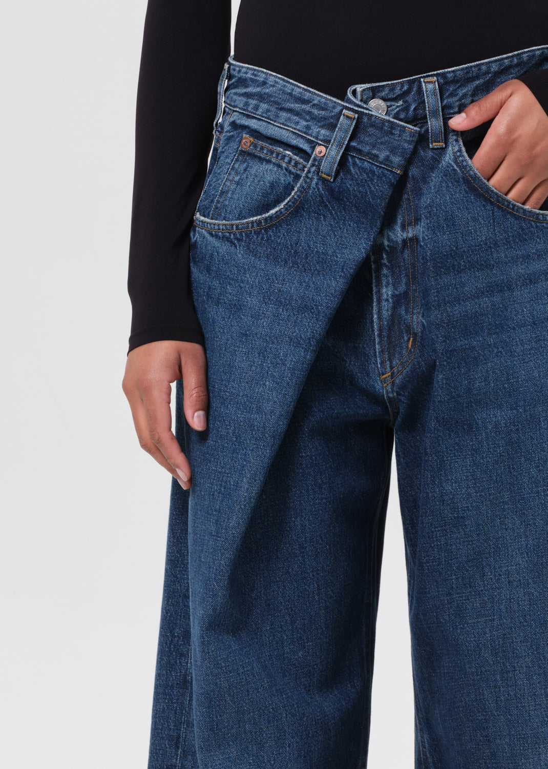 Person wearing blue jeans with a plain background