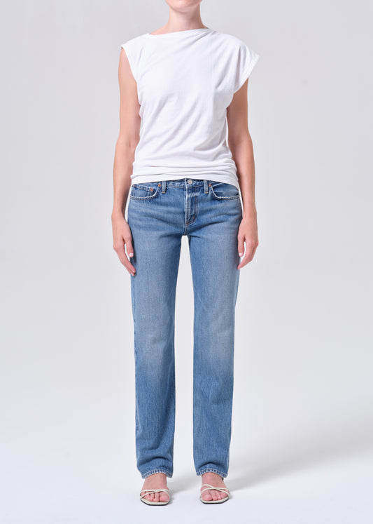 Person wearing a white t-shirt and light blue jeans on a plain background