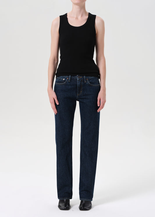 Person wearing a black sleeveless top and dark blue jeans on a white background