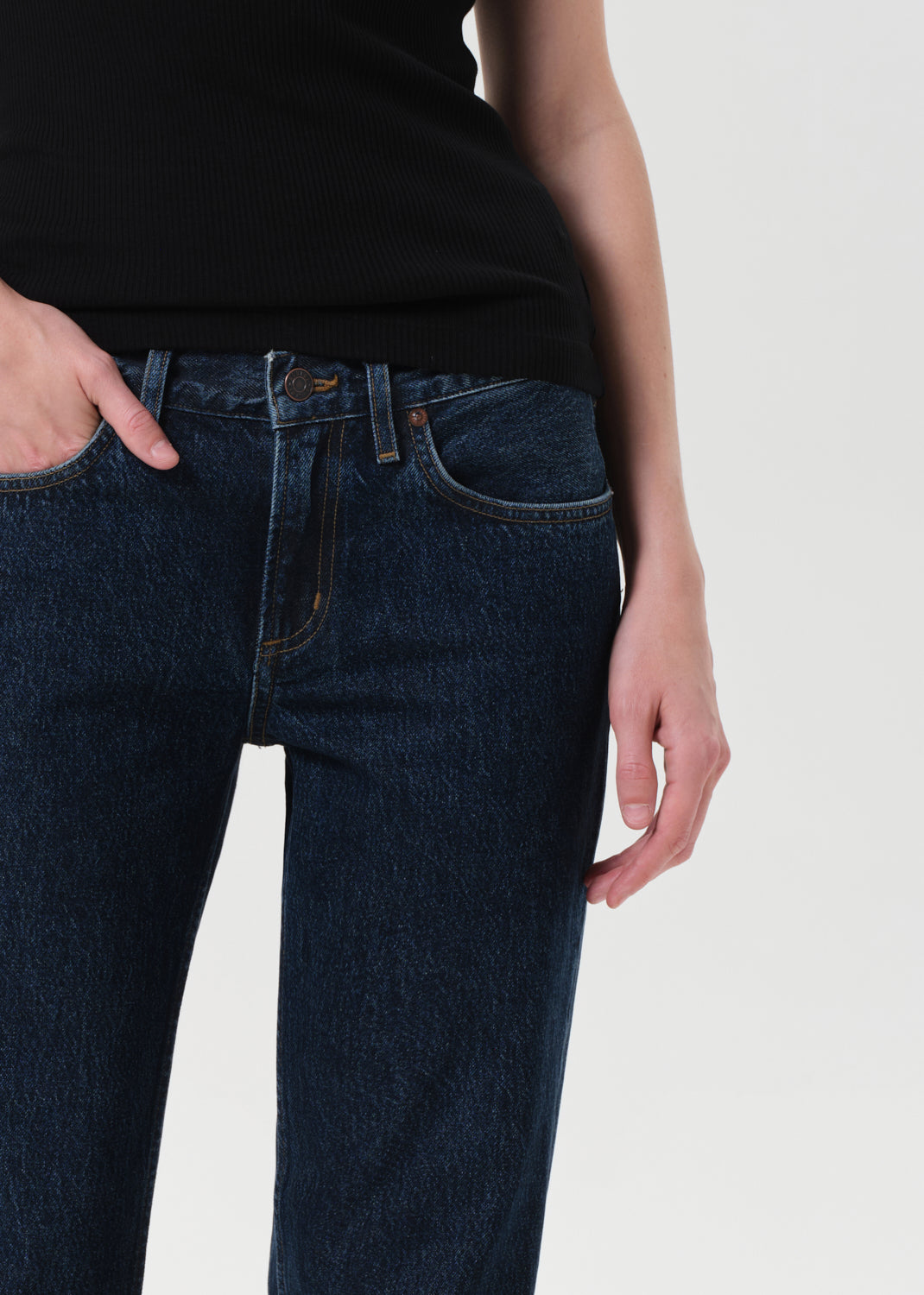 Person wearing dark blue jeans and a black top on a white background