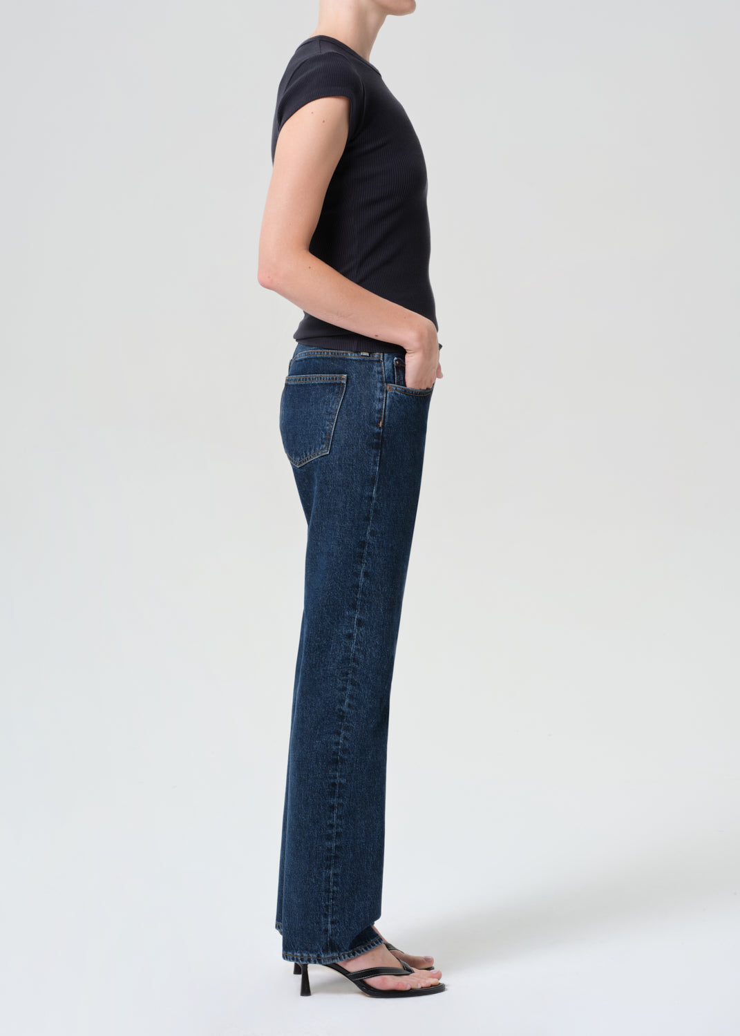Person wearing dark blue jeans and a black top on a white background