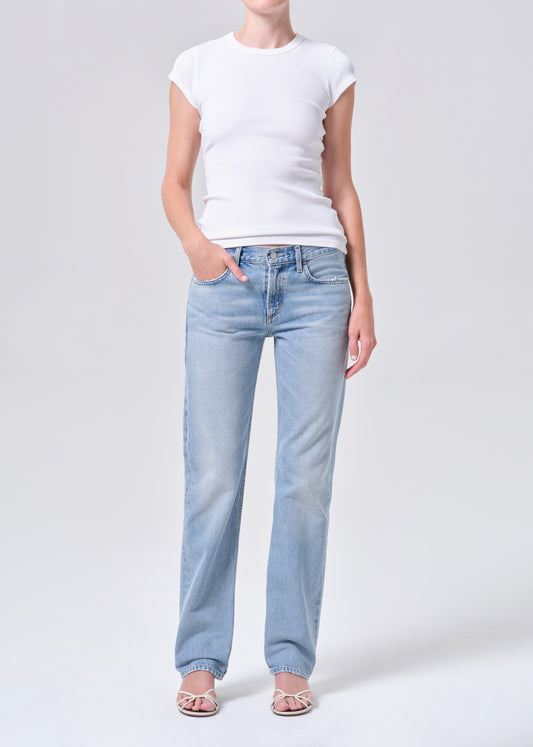 Person wearing light blue jeans and a white t-shirt on a plain background