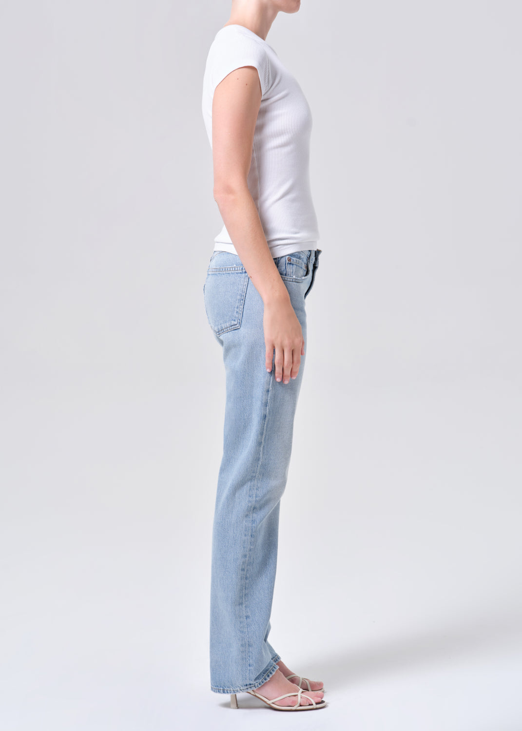 Person wearing light blue jeans and a white t-shirt on a plain background