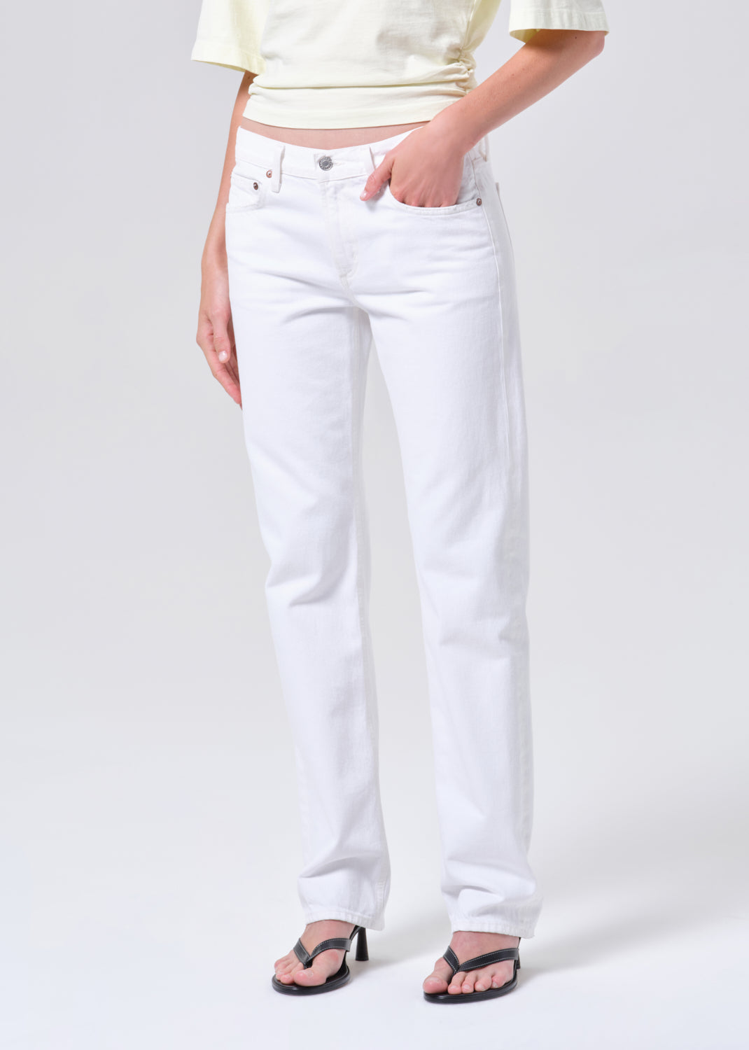 Person wearing white jeans on a plain background