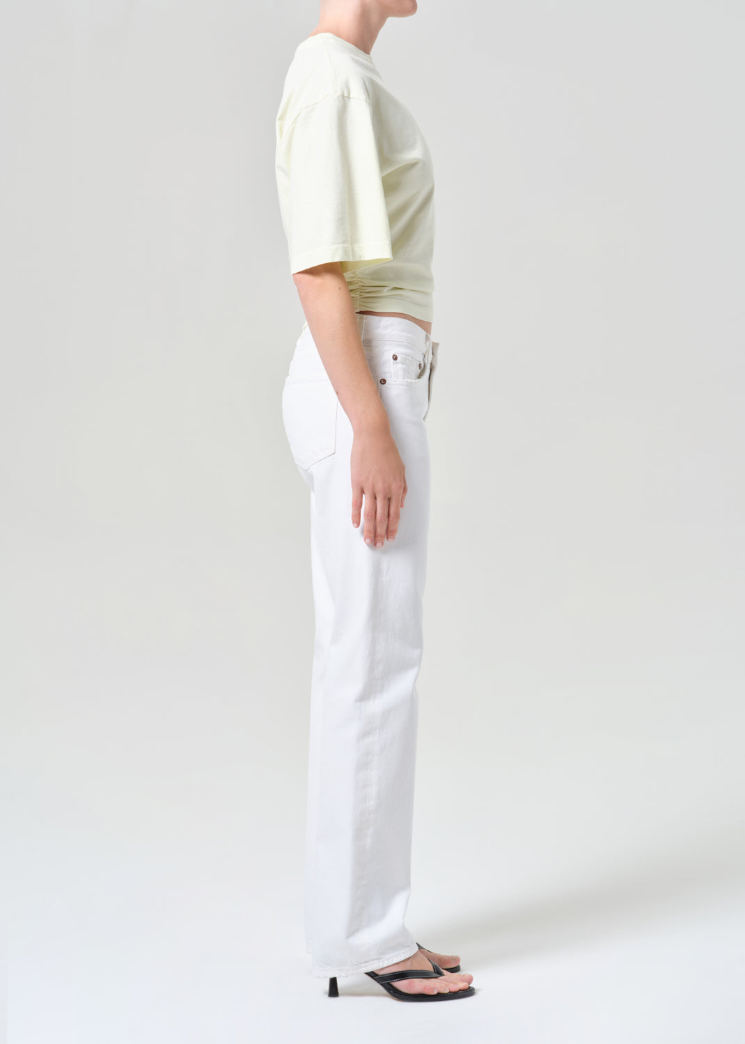 Person wearing a light-colored top and white pants on a plain background