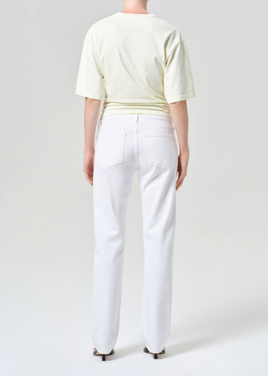 Person wearing a light-colored top and white pants on a plain background