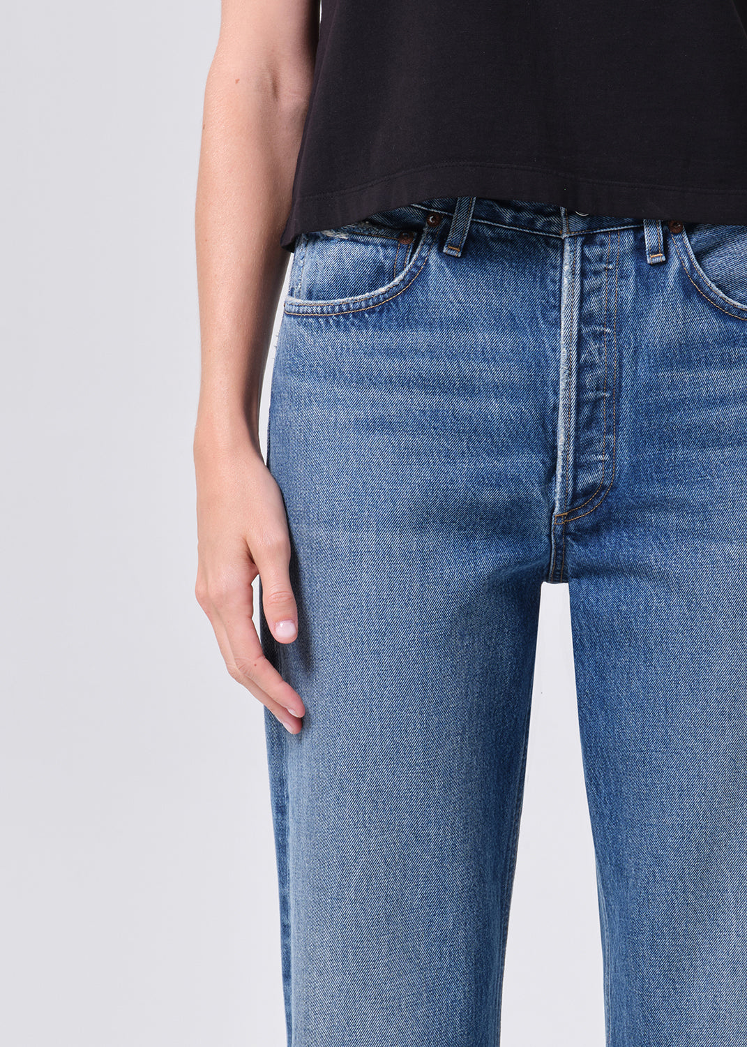 Person wearing blue jeans on a plain background