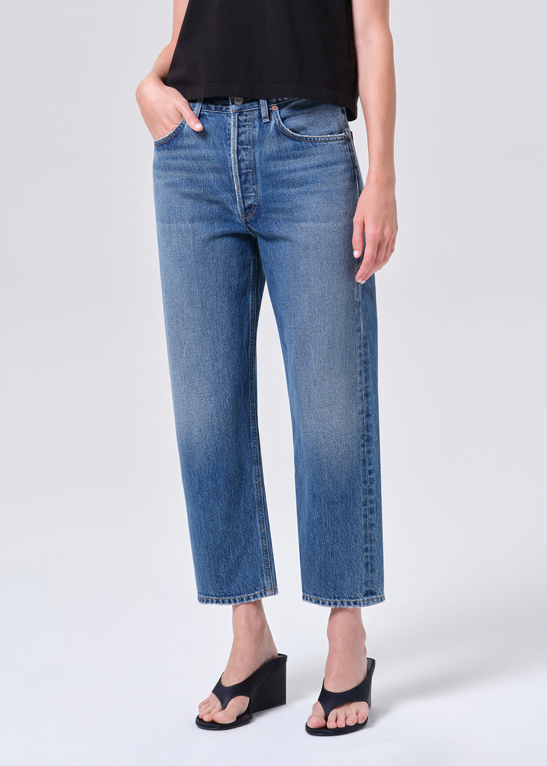 Person wearing blue jeans on a plain background