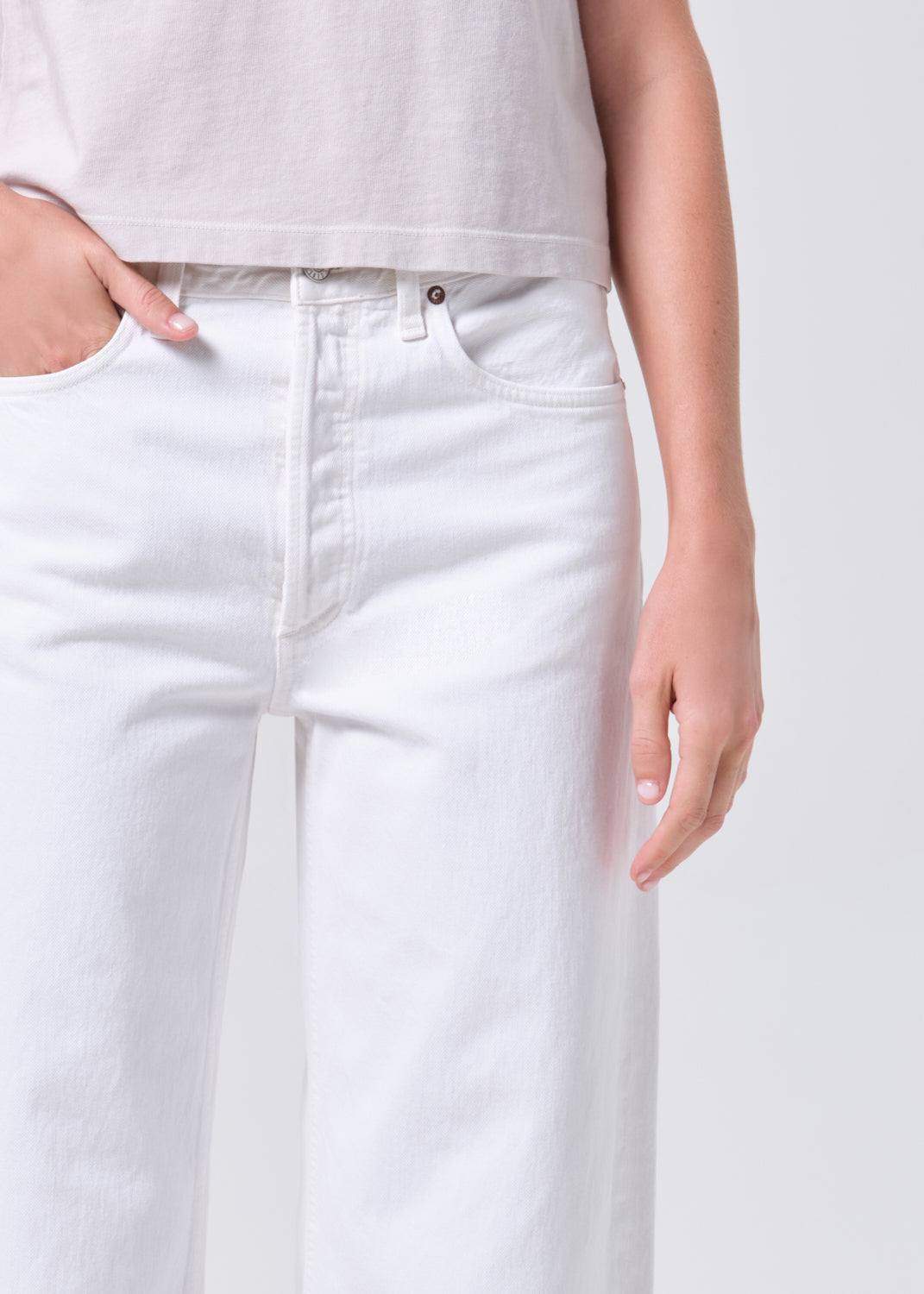 White jeans worn by a person on a plain background