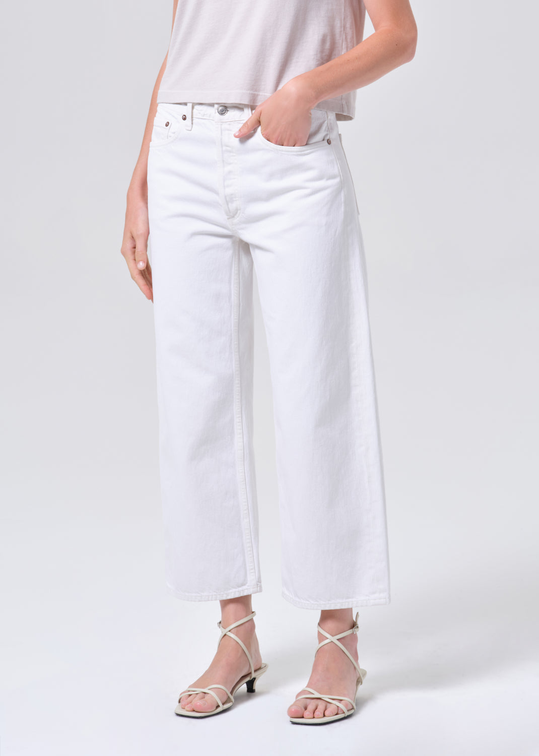 Person wearing white jeans on a plain background