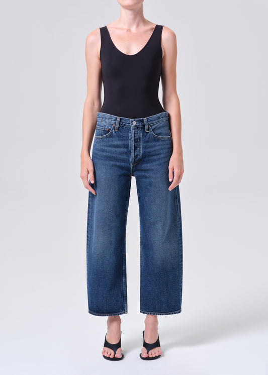 Person wearing a black tank top and blue jeans on a white background