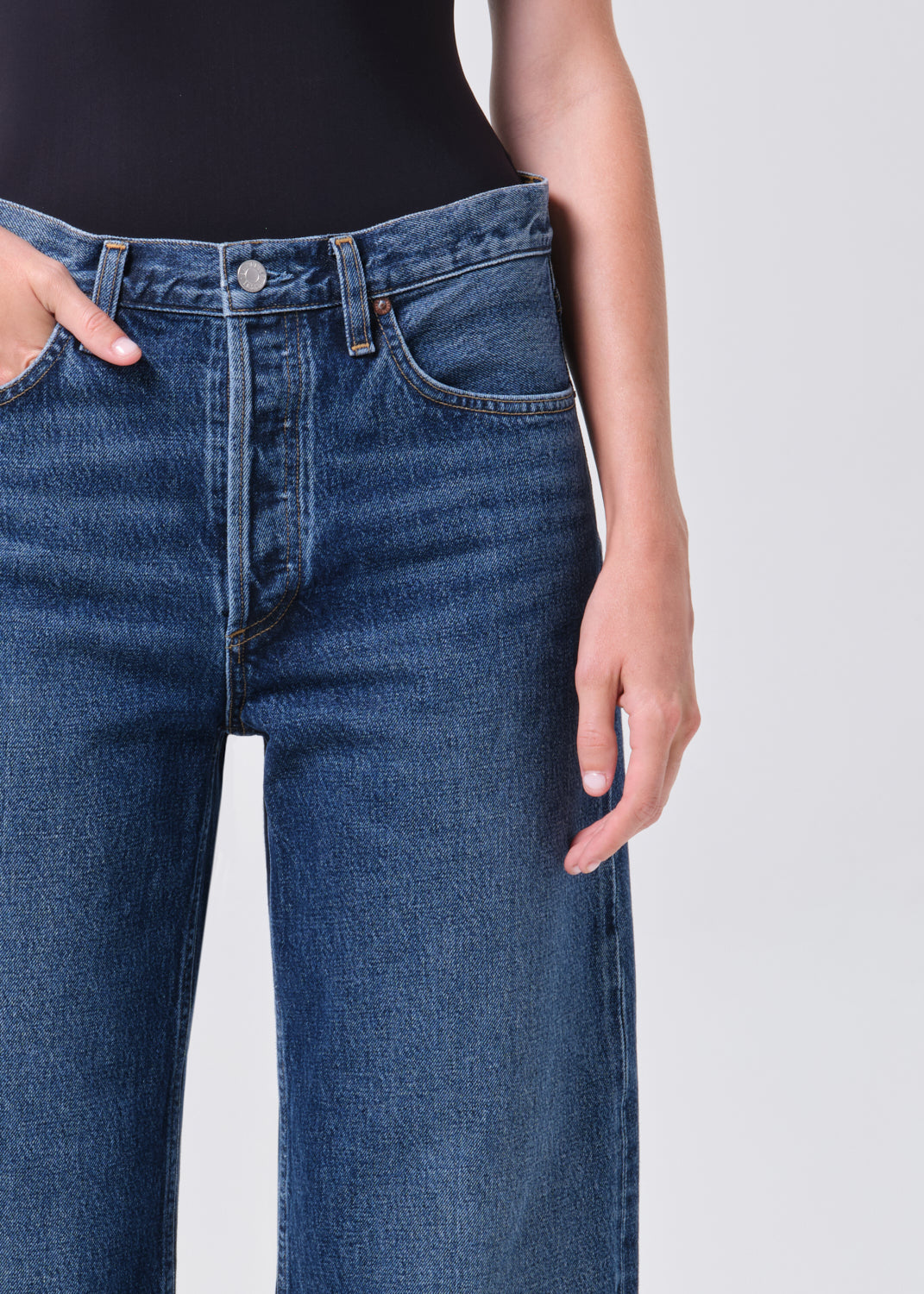 Person wearing blue jeans on a plain background