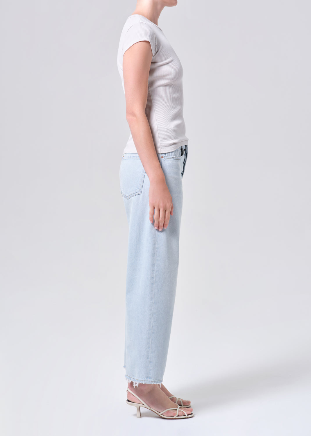 Person wearing a light gray t-shirt and light blue jeans on a white background