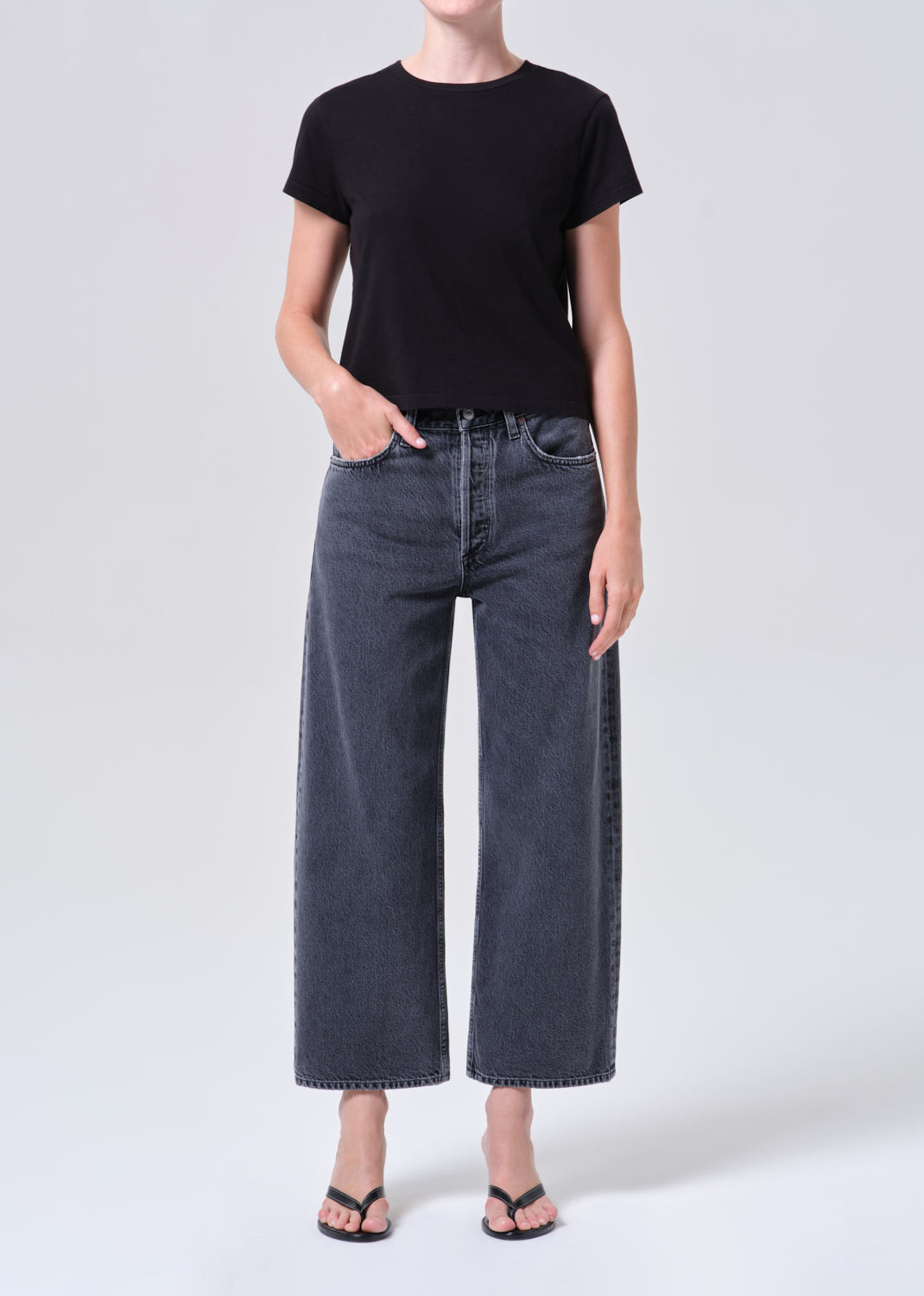 Person wearing a black t-shirt and dark blue jeans on a white background