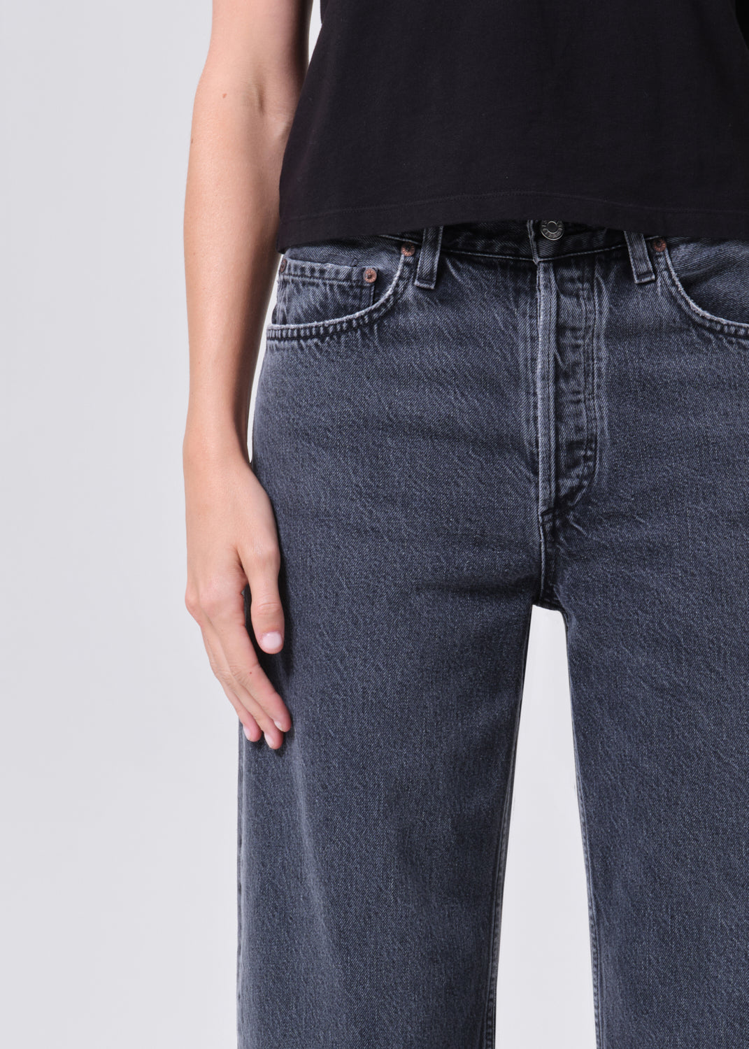Person wearing dark blue jeans on a light gray background