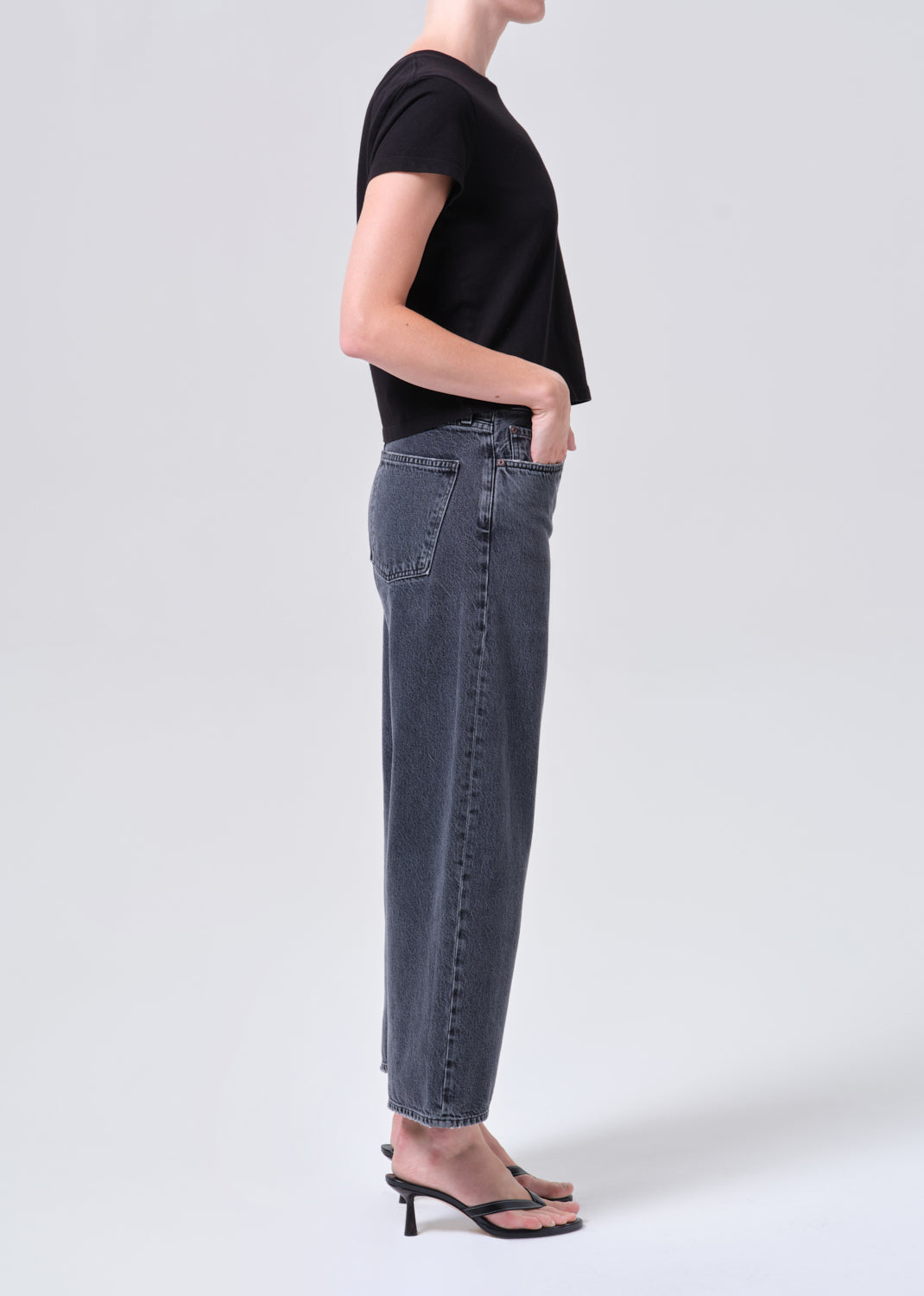 Person wearing a black t-shirt and blue jeans on a white background