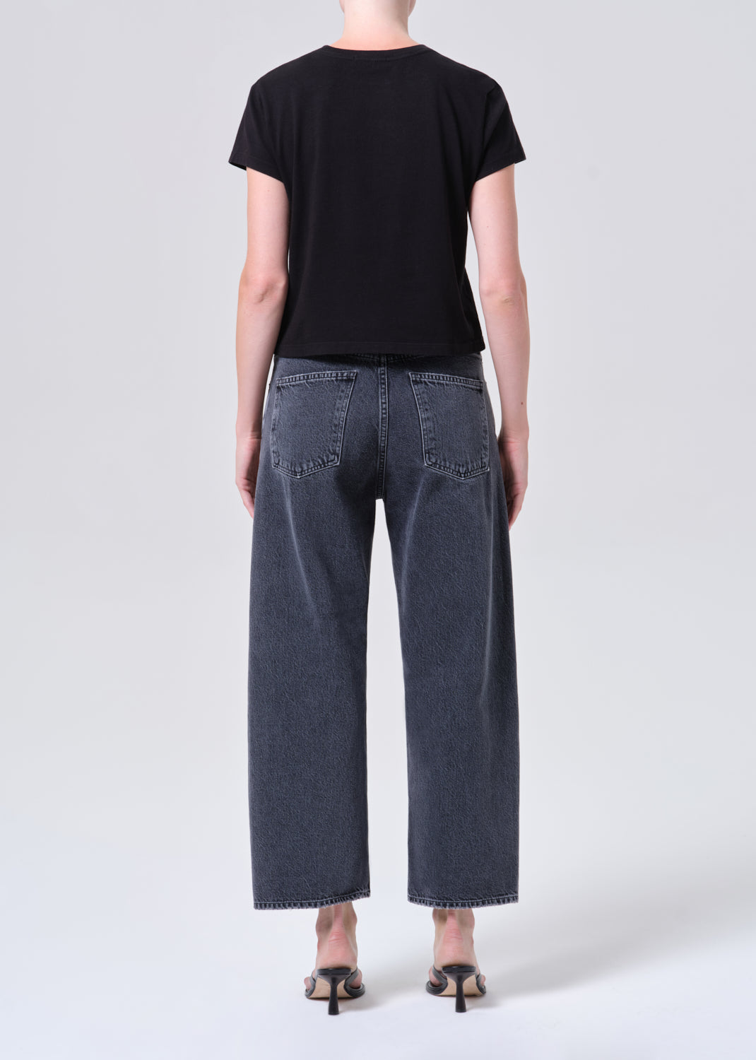Person wearing a black t-shirt and dark blue jeans on a white background