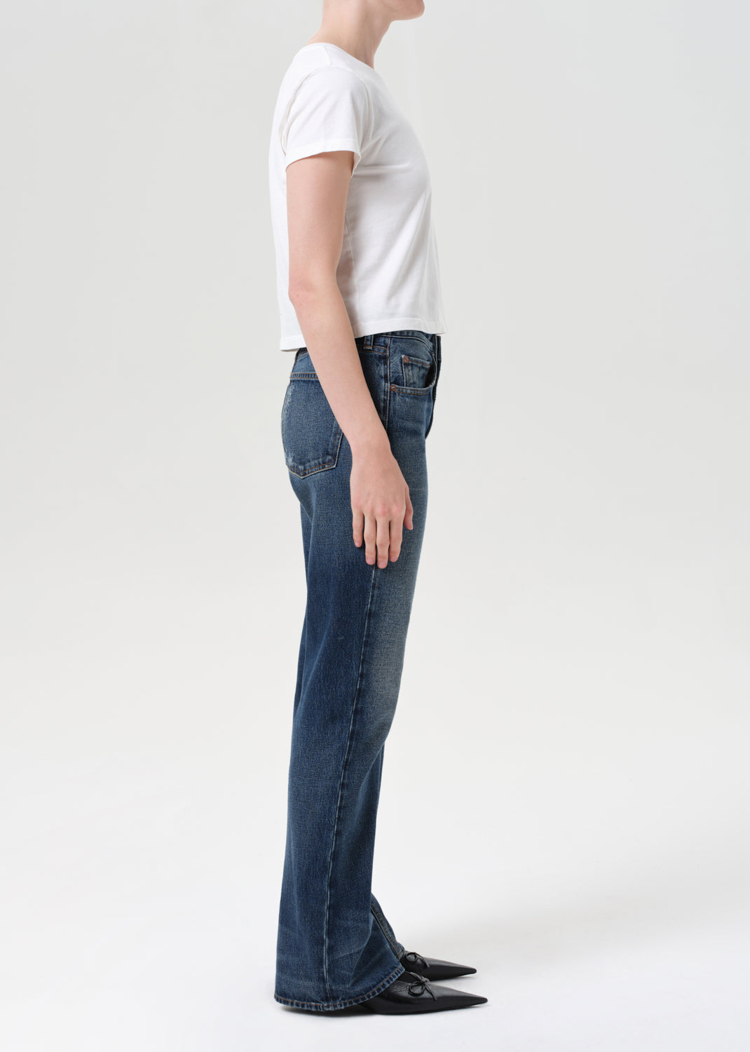 Person wearing blue jeans and a white t-shirt on a white background