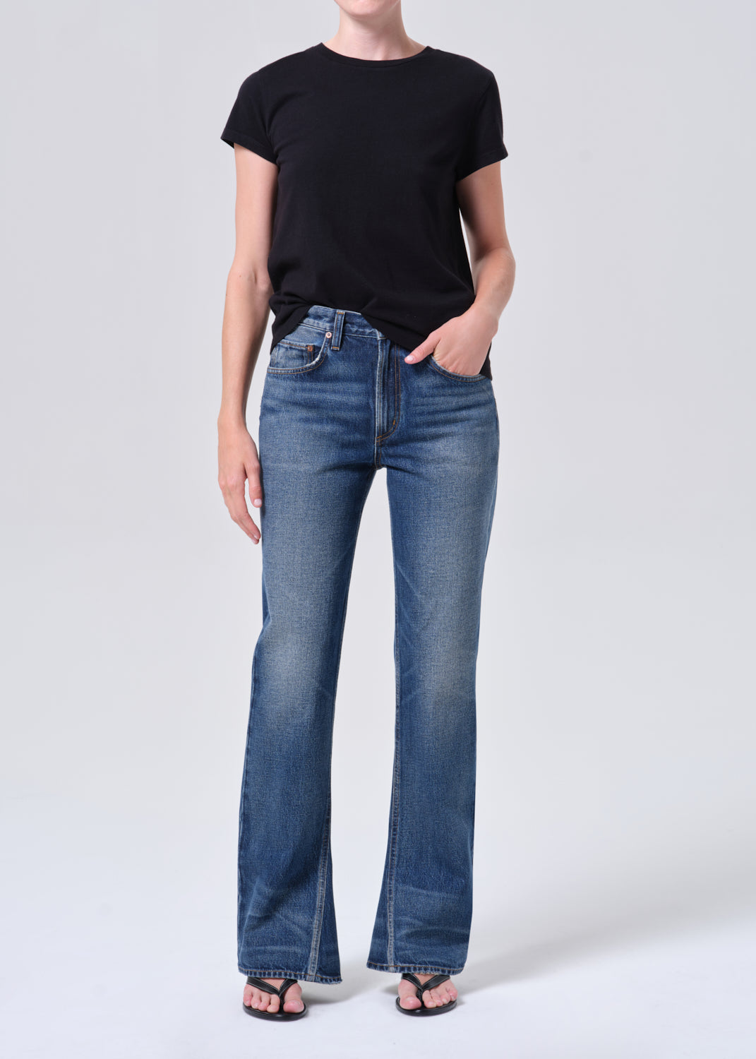 Person wearing a black t-shirt and blue jeans on a white background