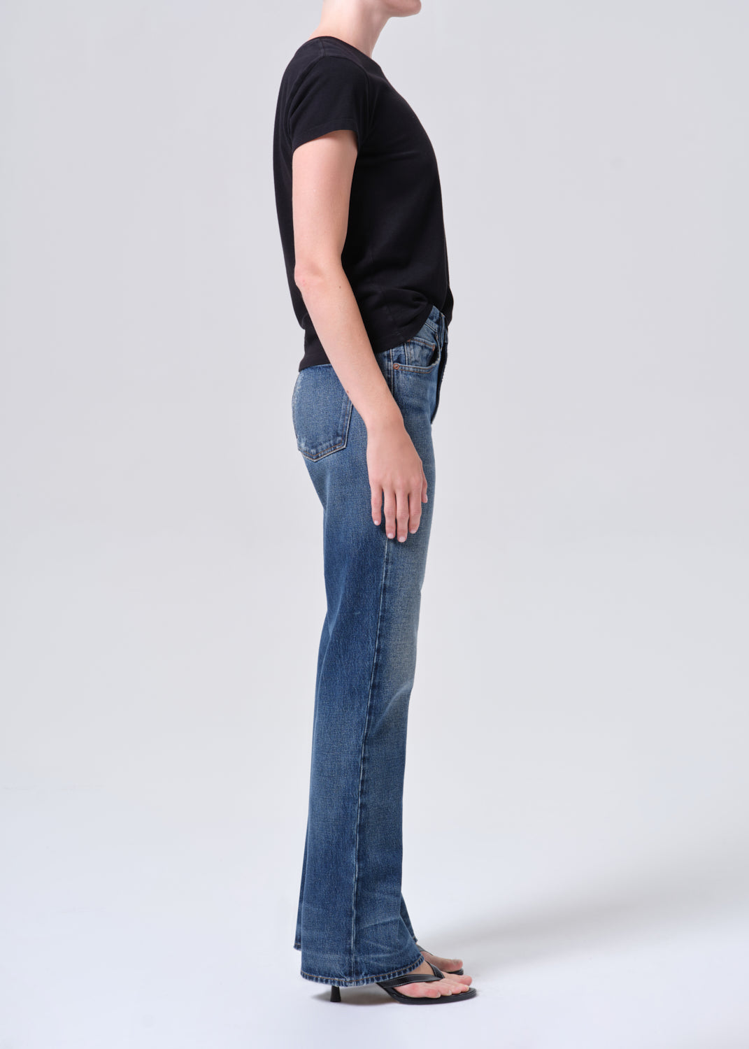 Person wearing a black t-shirt and blue jeans on a white background
