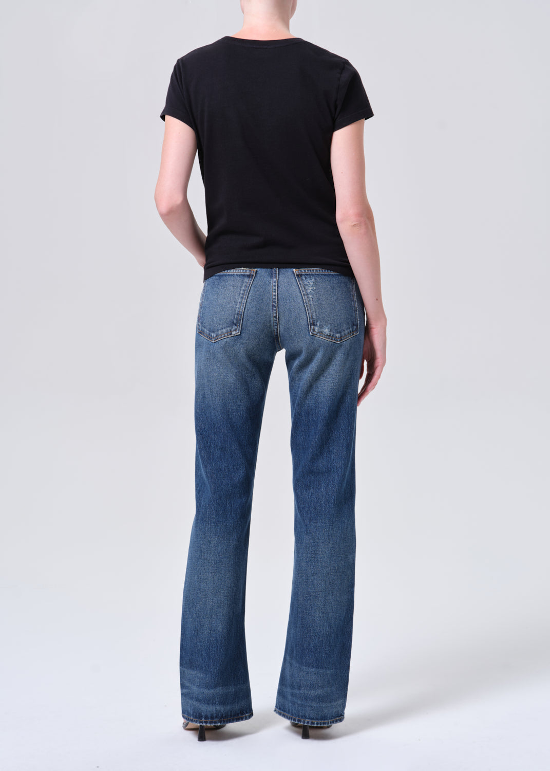 Person wearing blue jeans and a black t-shirt on a white background