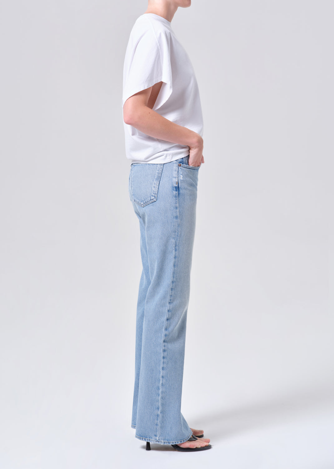 Person wearing light blue jeans and a white shirt on a plain background